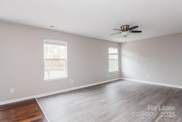 a view of an empty room with a window and wooden floor