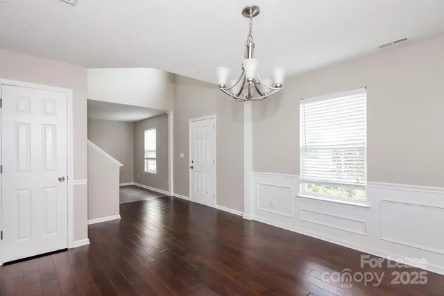 a view of a livingroom with wooden floor a ceiling fan and windows