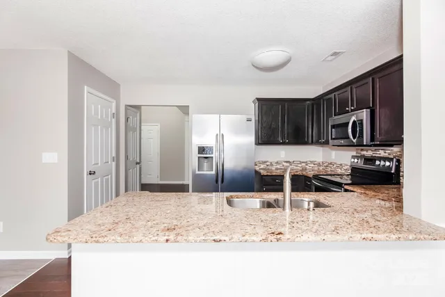 a kitchen with stainless steel appliances granite countertop a sink refrigerator and cabinets