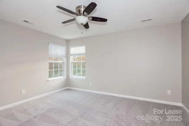 an empty room with a window and a fan