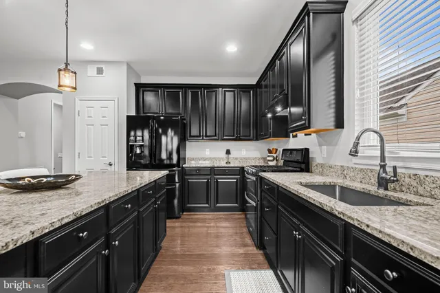 a kitchen with stainless steel appliances granite countertop sink stove top oven and cabinets