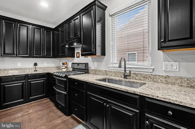 a kitchen with granite countertop cabinets a sink stainless steel appliances and a window
