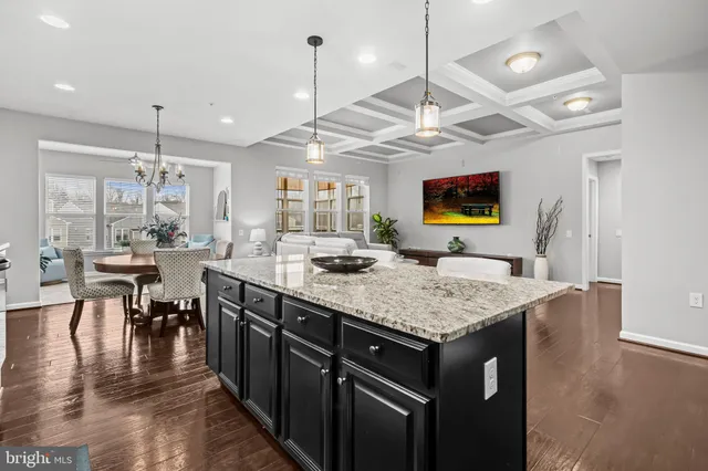 a kitchen with stainless steel appliances granite countertop center island a stove a dining table chairs and couches
