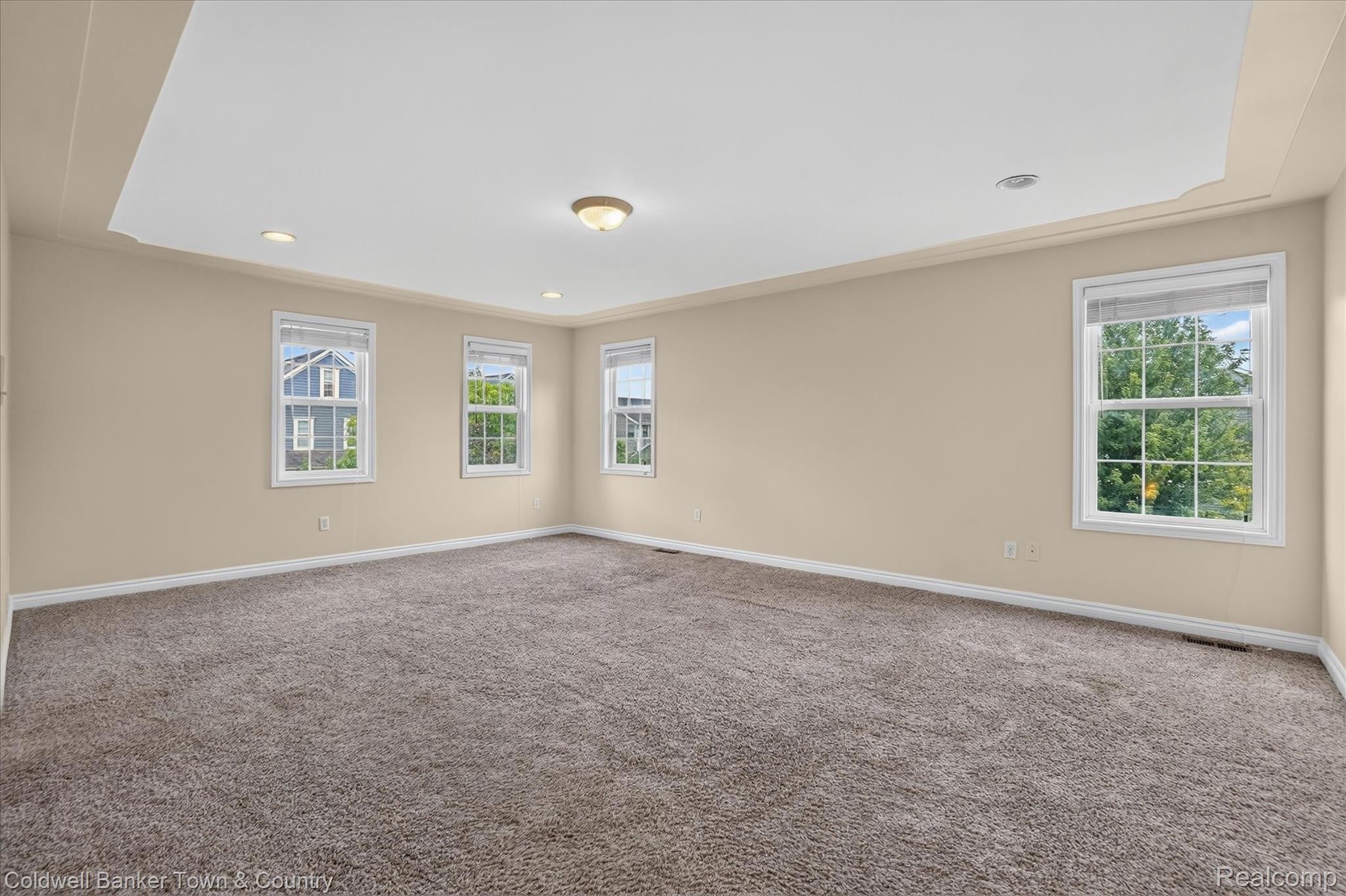 1725 Town Commons Drive Howell, MI 48855 - Photo 29 of 53 Spacious room featuring neutral carpeting, light beige walls, and a tray ceiling with recessed lighting