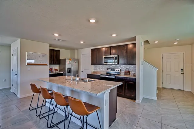 a kitchen with a sink a microwave a refrigerator and chairs