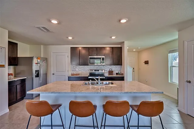a kitchen with stainless steel appliances a dining table chairs refrigerator and microwave