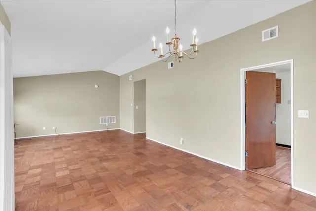 a view of an empty room with a chandelier fan