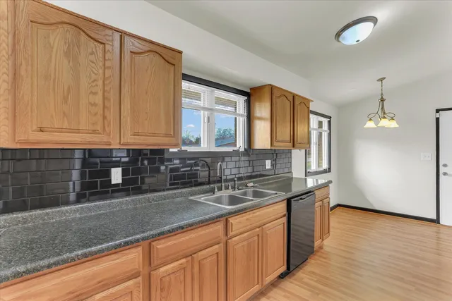 a kitchen with stainless steel appliances granite countertop a sink a stove and a wooden cabinets