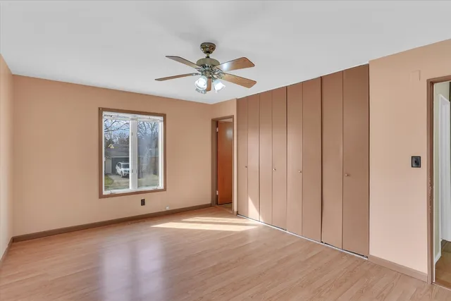 an empty room with wooden floor chandelier fan and windows