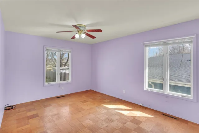 an empty room with windows and fan