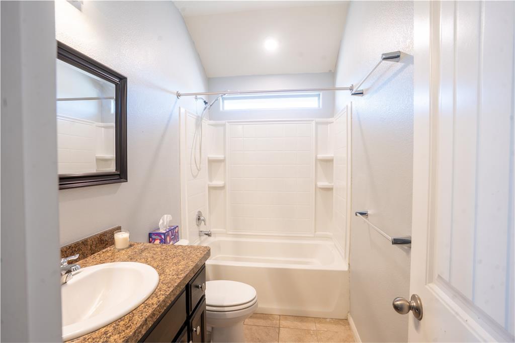 753 Rutherford Drive Crowley, TX 76036 - Photo 24 of 26 Bathroom featuring a single vanity with a stone-finish countertop, a drop-in sink, and a dark wood-finish cabinet