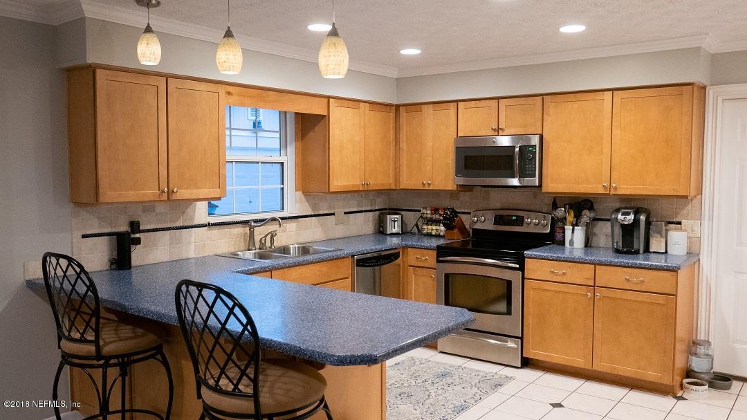 8918 San Rae Road Jacksonville, FL 32257 - Photo 17 of 33 a kitchen with stainless steel appliances granite countertop a stove a sink a microwave a dining table and chairs with wooden floor