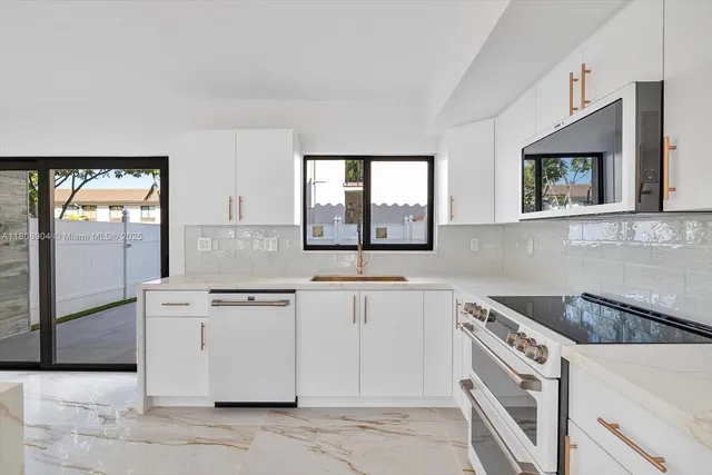 a kitchen with stainless steel appliances granite countertop a stove a sink and a microwave