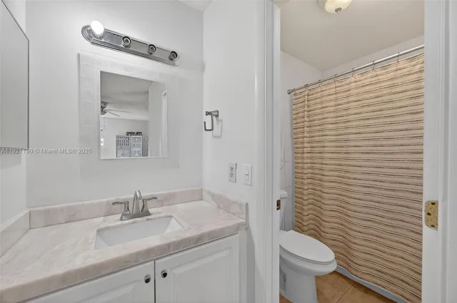 a bathroom with a granite countertop sink toilet and mirror