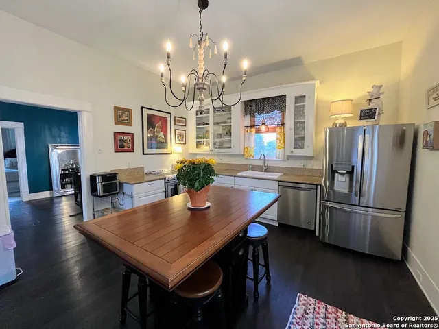 a kitchen with stainless steel appliances granite countertop a refrigerator a stove a kitchen island a dining table and chairs