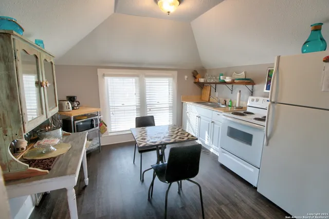 a kitchen with a refrigerator a stove a sink and dining table with wooden floor