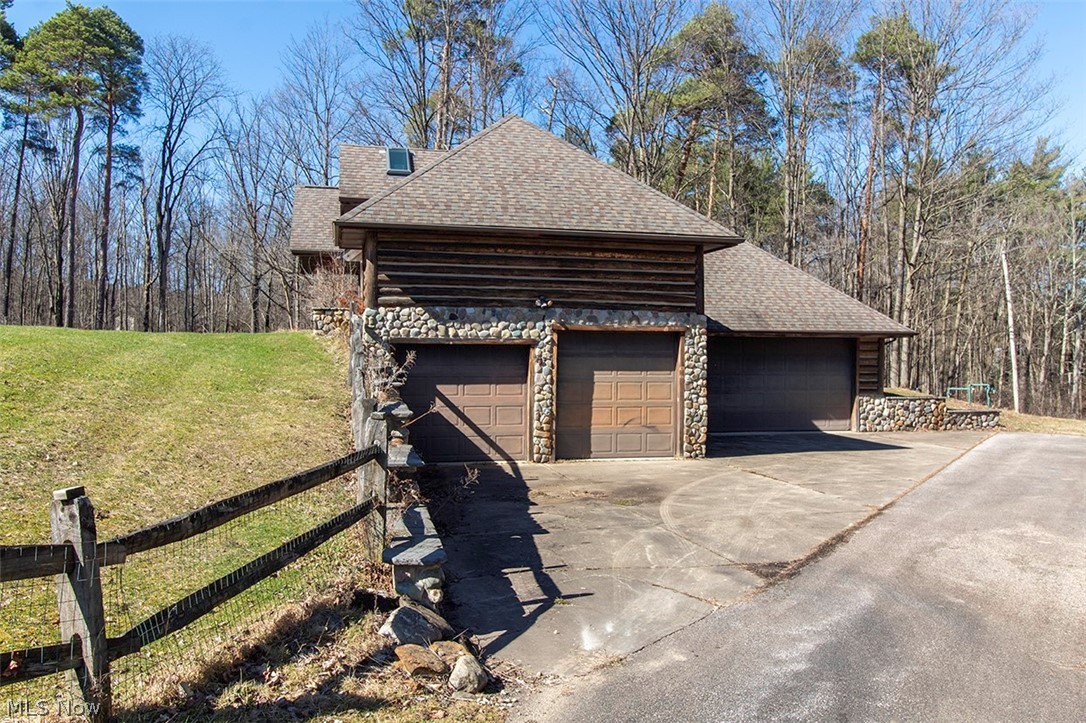 1871 Mattingly Road Hinckley, OH 44233 - Photo 47 of 50 View of home's exterior featuring roof with shingles, stone siding, driveway, a yard, and an attached garage