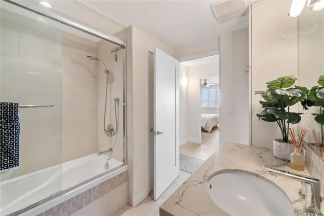 a bathroom with a granite countertop sink a mirror a bathtub and shower