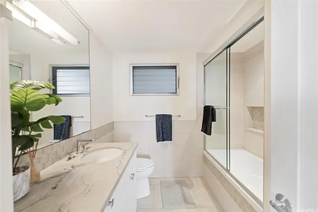 a bathroom with a granite countertop sink a mirror and shower