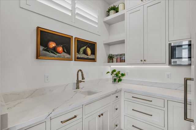2608 Canyon Ridge Drive St. George, UT 84770 - Photo 23 of 86 White shaker cabinetry with brass hardware, marble-look countertops, and an undermount sink with a bronze-finish faucet
