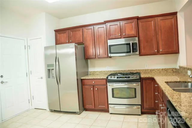 a kitchen with granite countertop a stove top oven microwave and refrigerator