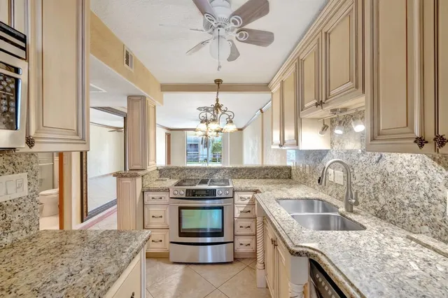 a kitchen with stainless steel appliances granite countertop a sink a stove and cabinets