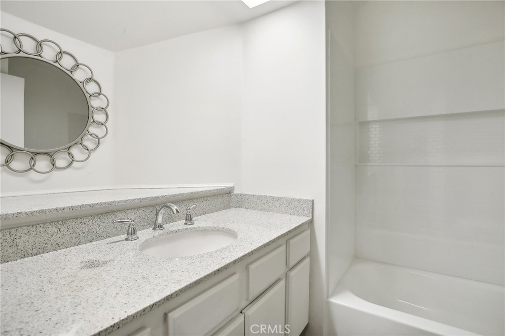 735 Wingate Bay, Unit 50 Costa Mesa, CA 92626 - Photo 14 of 32 a bathroom with a granite countertop sink and a mirror