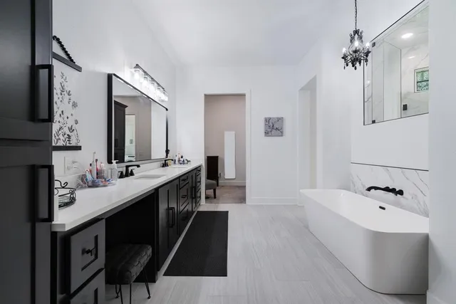 a bathroom with a double vanity sink a mirror a bathtub and a shower