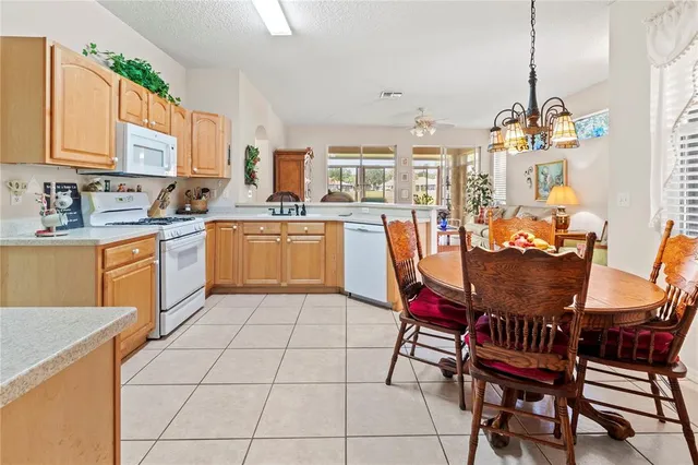 a kitchen with stainless steel appliances granite countertop a sink a stove a dining table and chairs