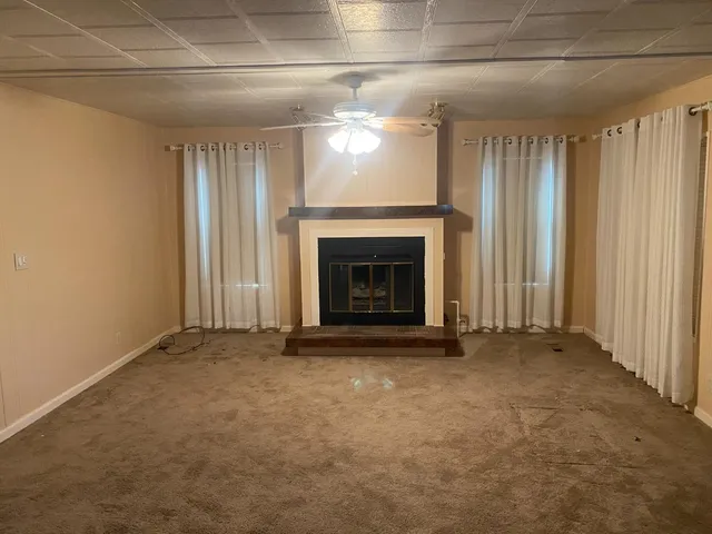 an empty room with windows and fireplace