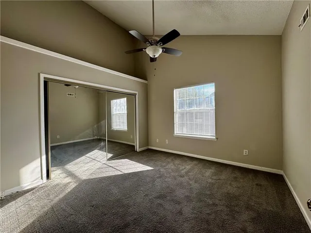 an empty room with windows and fan