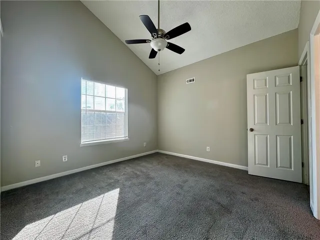 an empty room with windows and ceiling fan