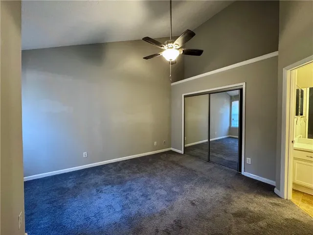 an empty room with a chandelier fan and windows