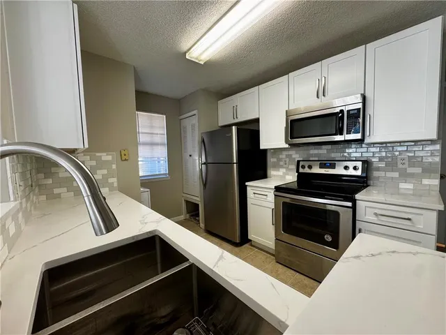 a kitchen with granite countertop a stove microwave and refrigerator