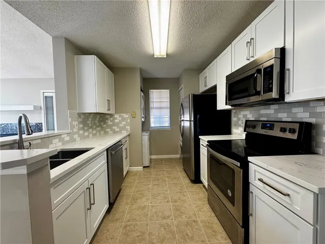 a kitchen with stainless steel appliances granite countertop a sink a stove a microwave and a refrigerator