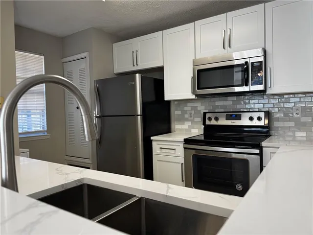 a kitchen with stainless steel appliances a stove microwave and refrigerator