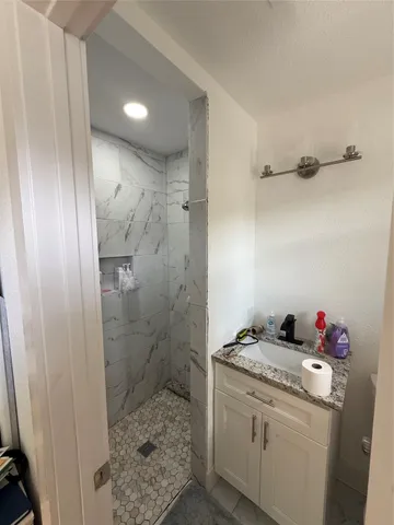 a bathroom with a granite countertop sink a toilet and shower