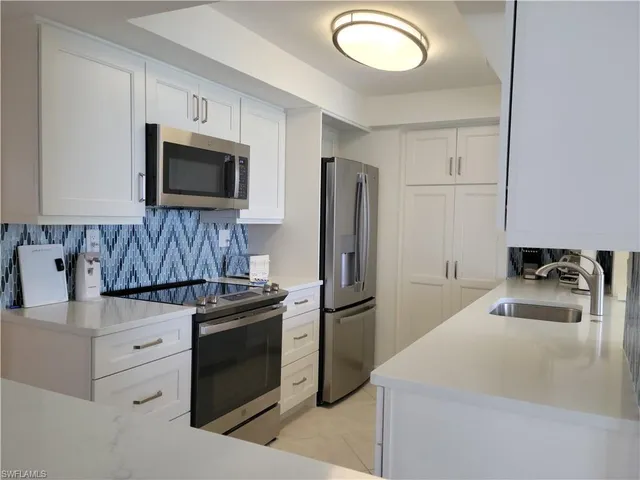 a kitchen with granite countertop a stove microwave and refrigerator
