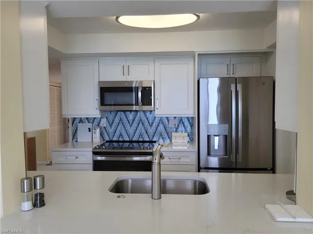 a kitchen with granite countertop a refrigerator and a stove top oven