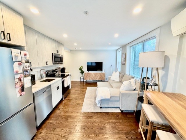 a large room with kitchen island white cabinets and stainless steel appliances