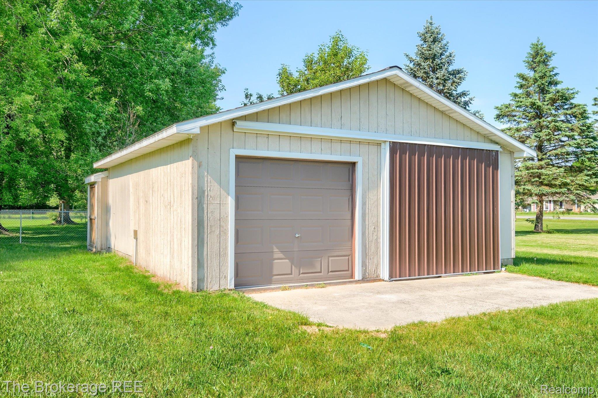 5495 East Coldwater Road Flint, MI 48506 - Photo 3 of 44 Detached outbuilding featuring a single garage door, a large sliding panel door, a concrete pad, a side entry door, and a pitched roof