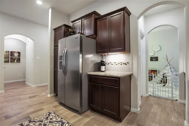 a kitchen with stainless steel appliances granite countertop a refrigerator a stove and a sink with wooden floor