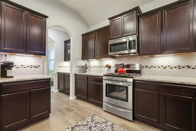 a kitchen with stainless steel appliances granite countertop a stove microwave and sink