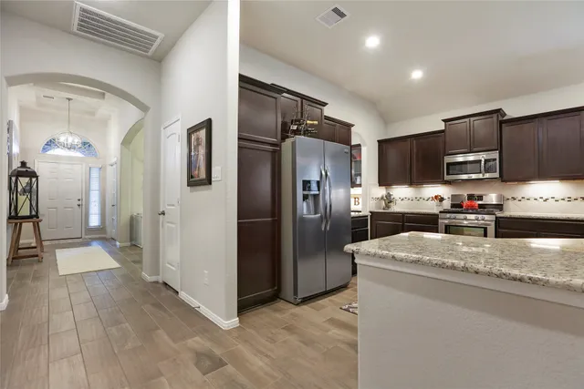 a kitchen with stainless steel appliances granite countertop a refrigerator a stove and a sink