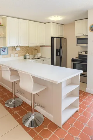 a kitchen with kitchen island a counter top a stove a refrigerator and a sink