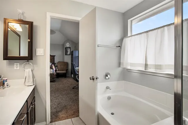 a bathroom with a tub sink and mirror