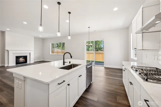 a kitchen with stainless steel appliances granite countertop a sink a stove and a wooden floors