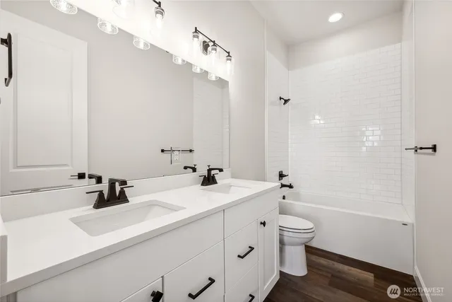 a bathroom with a double vanity sink toilet mirror and shower