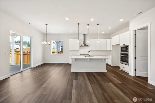a large kitchen with a large window a sink stainless steel appliances and cabinets