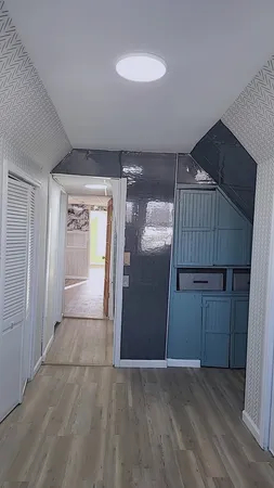 an empty room with wooden floor cabinet and windows